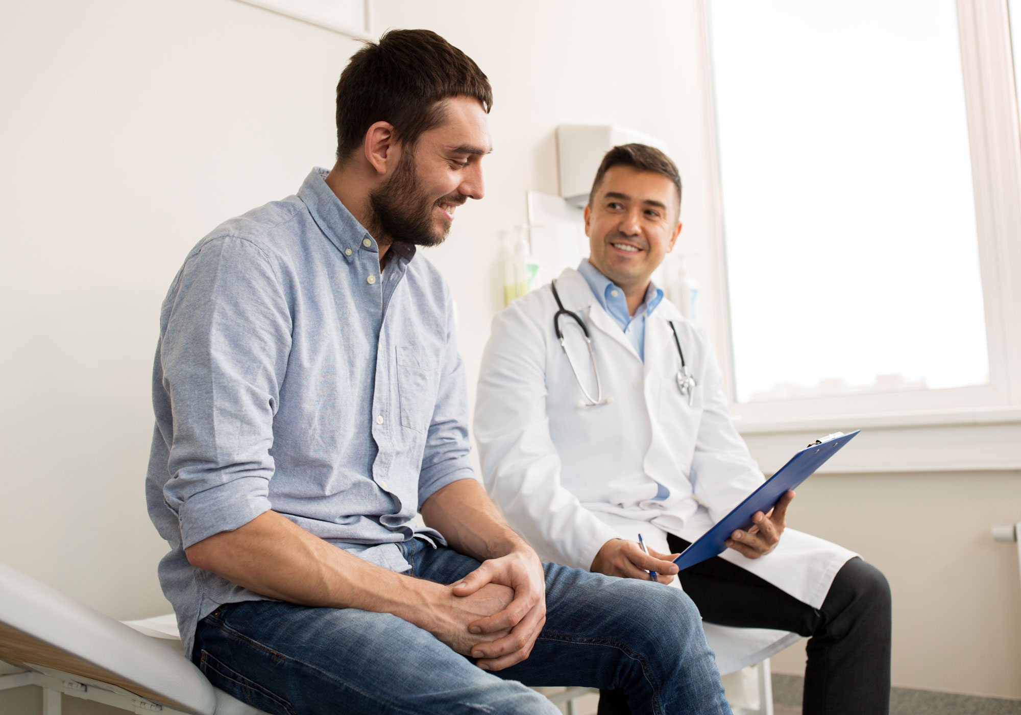 male patient and male doctor sitting on bed
